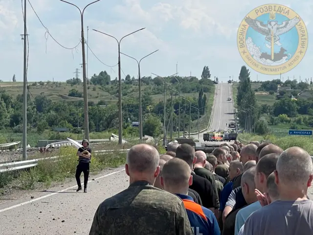 A man with a white flag walks along the road during an exchange of prisoners, at a location given as Zaporizhzhia region, Ukraine