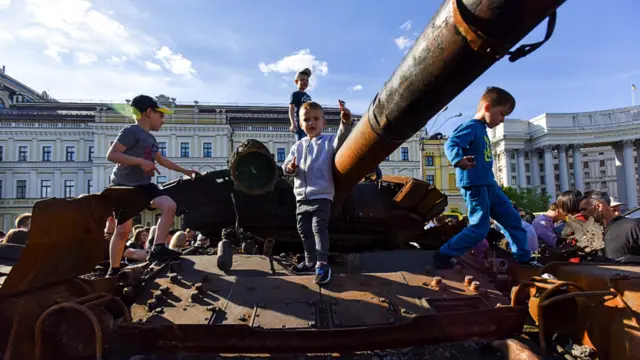 Children climb on a destroyed Russian tank in Ukraine's capital Kyiv