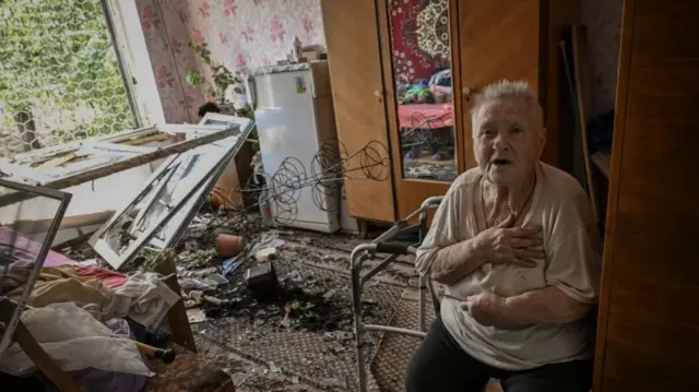 An elderly woman is pictured in her damaged apartment after an attack in the city of Soledar, 4 June 2022