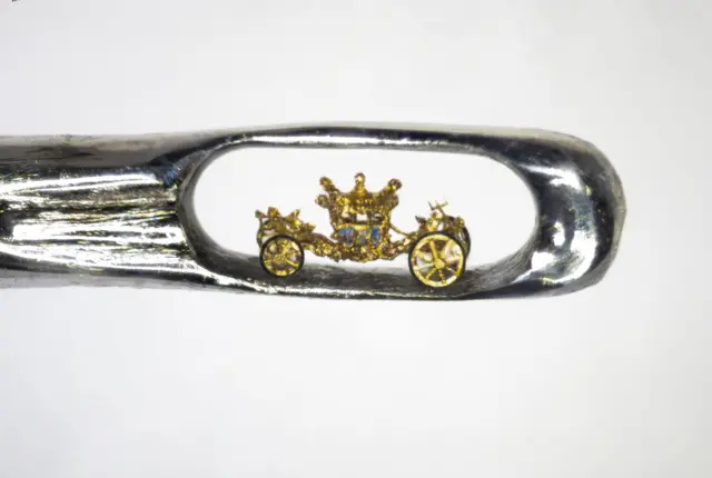 A close-up of a miniature Queen's Coronation Carriage inside the eye of a needle