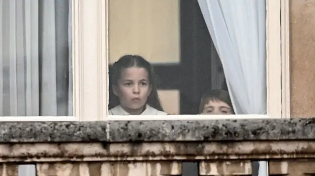 Princess Charlotte and Prince Louis peer through the palace window