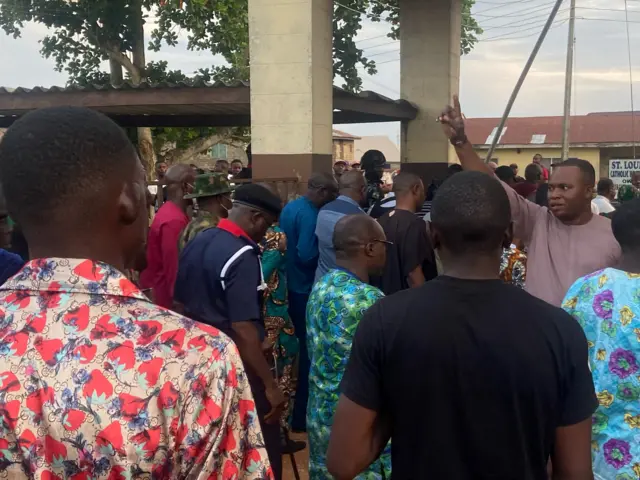 Relatives of churchgoers who were attacked by gunmen during Sunday's church service gather as health workers attend to victims brought in by ambulance after the attack at St Francis Catholic Church, in Owo