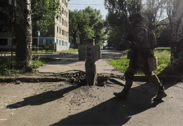 A Ukrainian soldier walks past part of a rocket in Severodonetsk