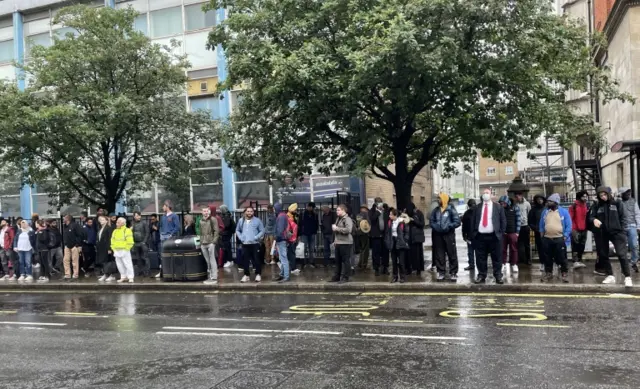 People stand at a bus stop