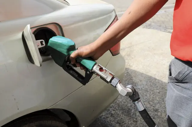 A man puts petrol in a car.