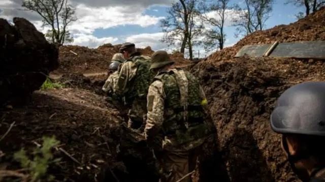 Soldiers walk in trenches to take cover for Russian artillery strikes at an undisclosed defence position near Donetsk