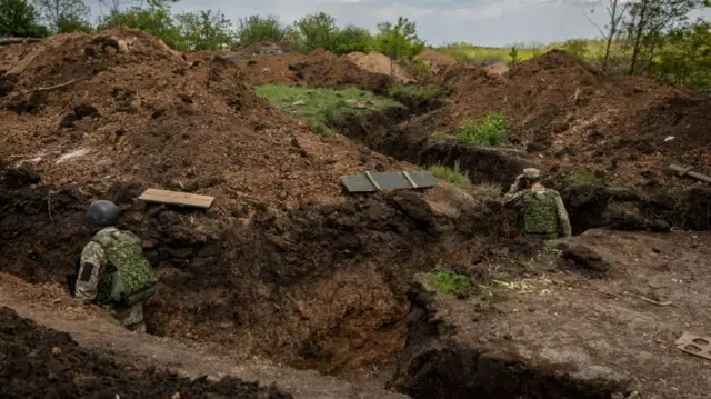 Two soldiers walk in a trench at an undisclosed defence position on the outskirt of the separatist region of Donetsk (Donbas).