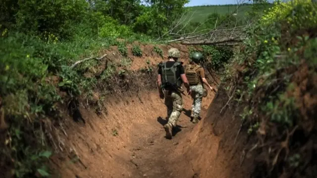 Ukrainian troops walk along a trench at a position on the front line near Bakhmut in Ukraine's Donbas region