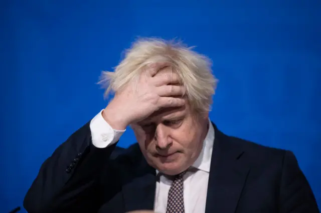 Boris Johnson is seen holding his head in one hand