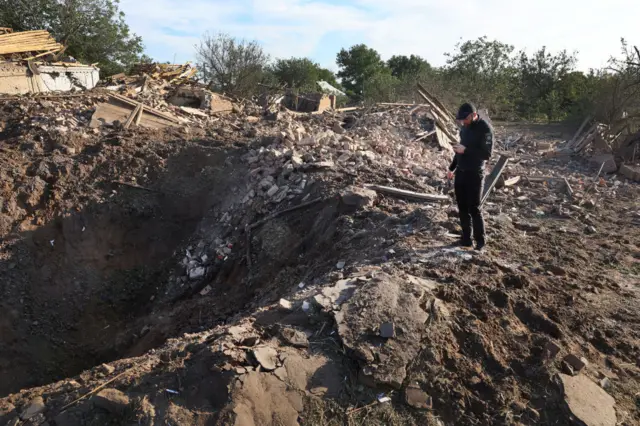 A police officer looks at a crater caused by a missile strike in the Donbas region
