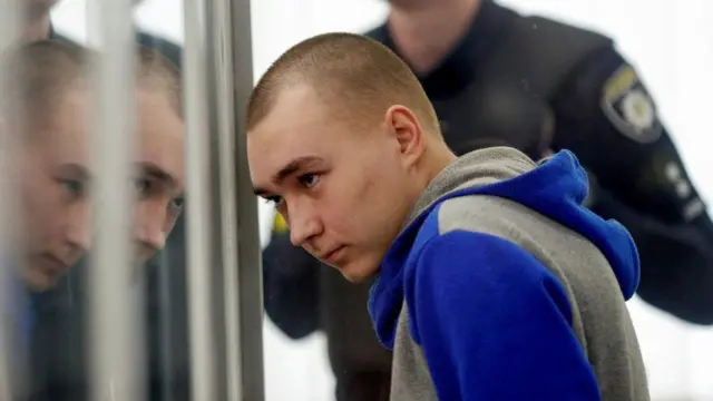 Russian solider Vadim Shishimari watches proceedings against him in a Kyiv courtroom