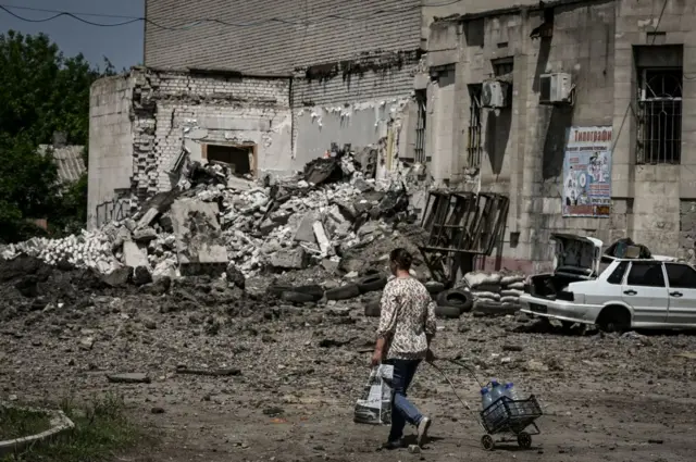 A woman walks past a wrecked building in Ukraine's Donbas region