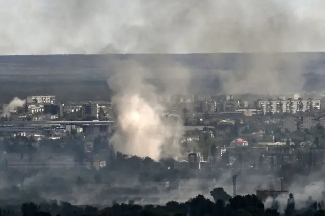 Smoke blows across rooftops