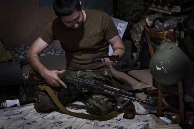 A Ukrainian serviceman checks his rifle