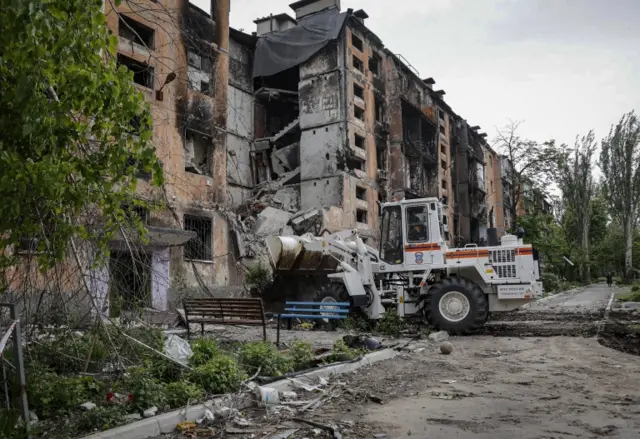 A Russian Emergency Ministry serviceman on a special truck clears the rubble of a destroyed house in Mariupol