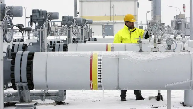 A worker stands next to a gas pipeline