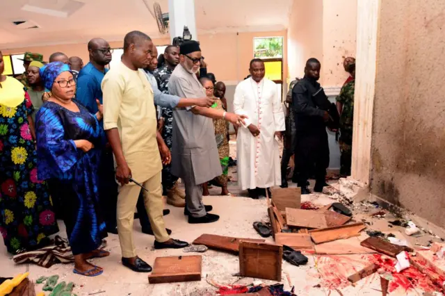 Ondo State governor Rotimi Akeredolu (3rd L) points to blood the stained floor after an attack by gunmen at St Francis Catholic Church in Owo town, southwest Nigeria on June 5, 2022.