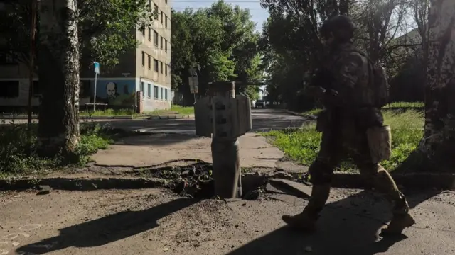 A Ukrainian soldier walks past a part of a rocket near the front line in the city of Severodonetsk, Luhansk region, Ukraine, 02 June 2022, where heavy fighting took place in the last few days.