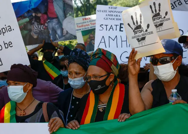 People hold up signs at a demonstration to bring awareness to the mass ethnic cleansing of ethnic Amharas in the Gimby Zone in Western Wollege, Oromia Region in Ethiopia on June 30, 2022 in Washington, DC.