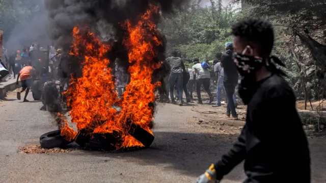 Anti-coup protesters walk past burning tires during clashes with security forces amidst mass demonstrations against military rule in the centre of Sudan's capital Khartoum on June 30, 2022