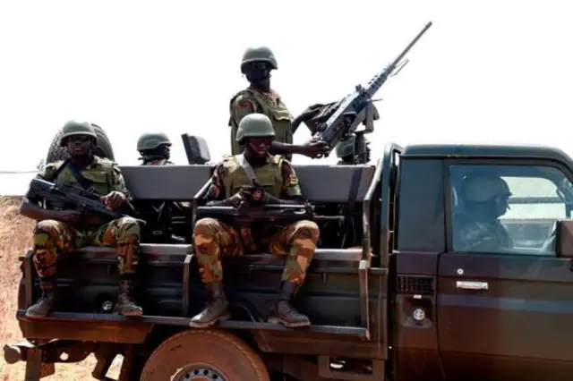 Togolese soldiers stand guard as they patrol at Namoundjoga village in northern Togo, on February 17, 2020.