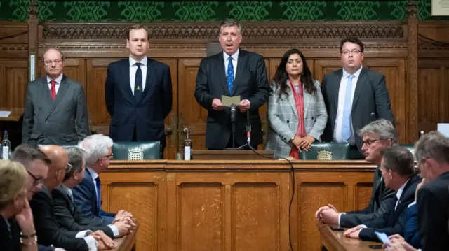 Sir Graham Brady reads out a bit of paper next to other MPs in a committee room in Parliament