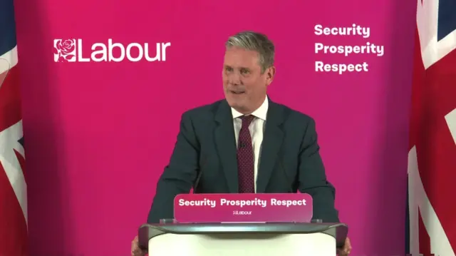 Sir Keir Starmer gives a speech in front of two Union Jack flags