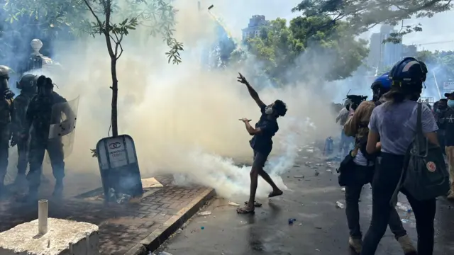 Protesters in Colombo throw back canisters of tear gas that were fired at them by police forces