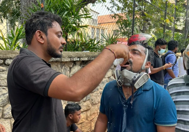 A man pours water into the face and eyes of another protester who was hit with tear gas