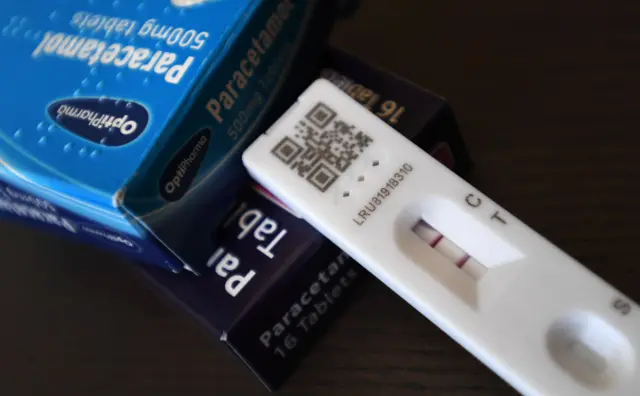 A Covid lateral flow test showing a positive result sits on a table