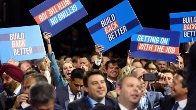 Image of the Conservative party conference in Manchester in 2021. Members of the crowd are holding signs which say "Build back better".