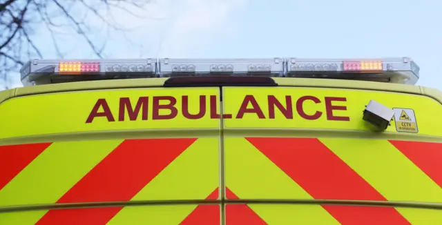 The top of an ambulance is seen, including flashing lights