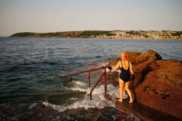 A woman prepares for a swim in the sea in Penzance, Cornwall