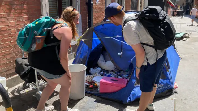 Charity workers check a tent on the pavement