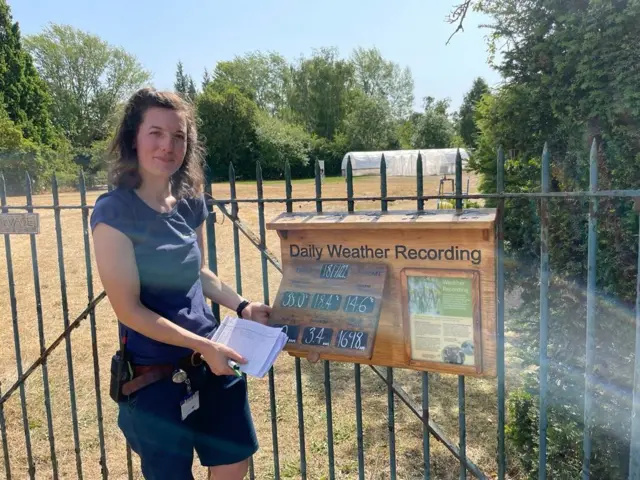 A woman with a daily weather recording board