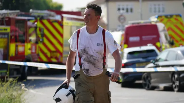 A firefighter grimaces in a soot-stained T-shirt