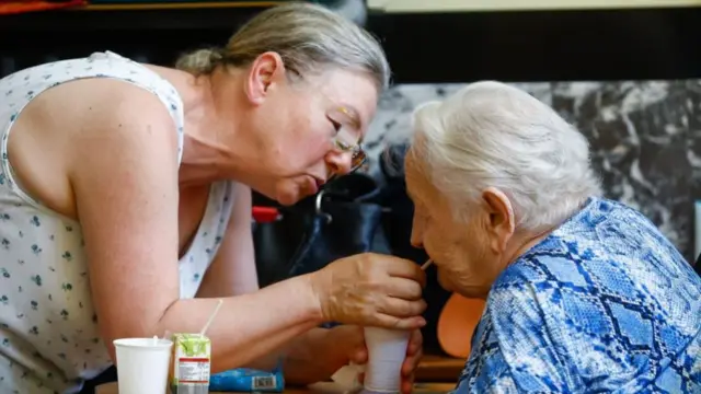 A resident of the nursing home is assisted to drink and hydrate with cold drinks made from ice water during the heat wave in their nursing home in the province of Hainaut in Chatelet, Belgium