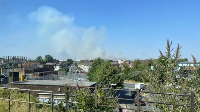 A view from a viaduct showing houses with smoke rising in the distance