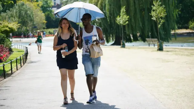 Two people under an umbrella in London's Regents Park during the heatwave