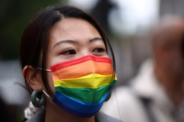 A person wears a rainbow coloured face mask