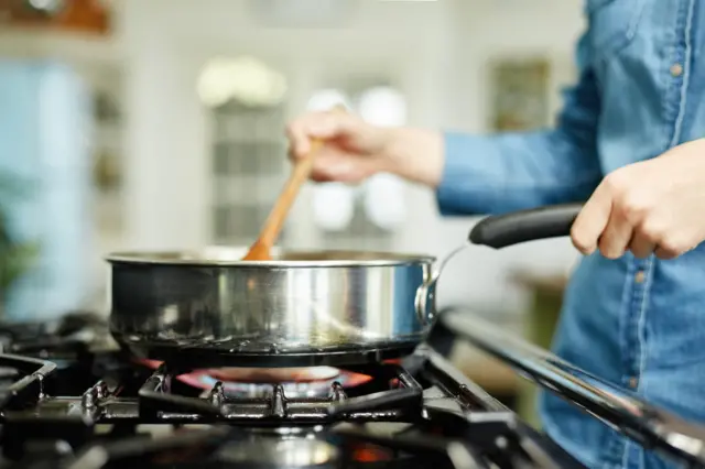 A woman cooks food in a pan