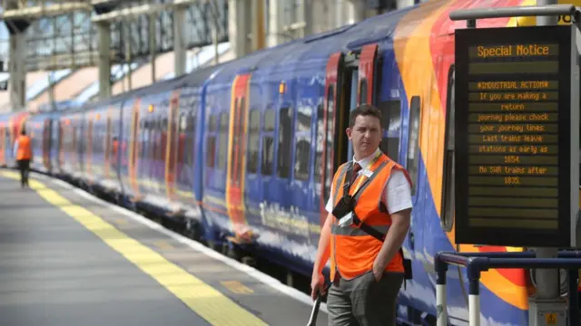 A rail worker stands next to a stationary train