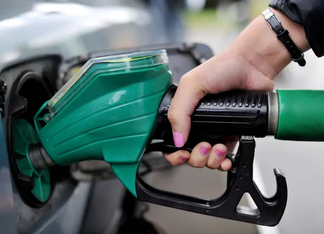 A woman fills her car with petrol