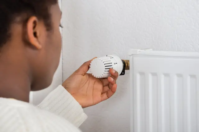 A woman adjusts the temperature of a radiator