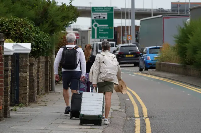 People make their way to the cruise terminal in Dover in Kent as no taxis or buses are available due to the traffic jams