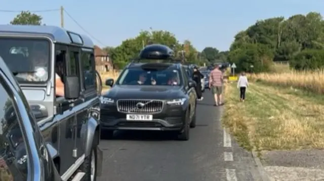 Cars queuing to get to the Eurotunnel at Folkestone and people standing outside their cars