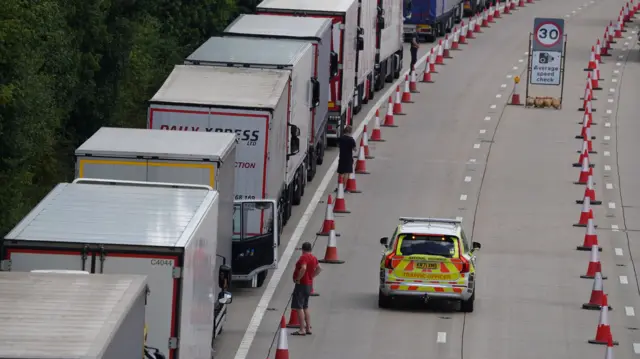 a police car parked alongside queuing lorries