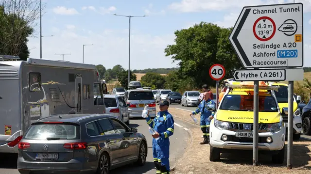 Members of the Coast Guard hand out bottled water to vehicles queuing to enter the Eurotunnel terminal in Folkestone