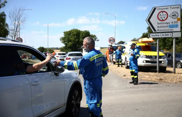 Members of the Coast Guard hand out bottled water to vehicles queuing to enter the Eurotunnel terminal in Folkestone