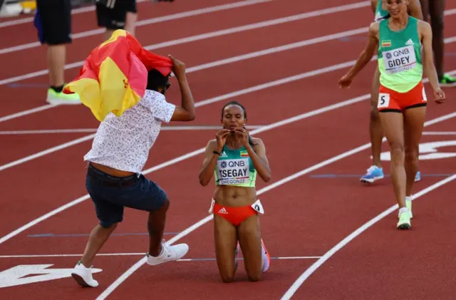 Ethiopias Gudaf Tsegay celebrates after winning the women's 5000 metres final as a spectator invades the track